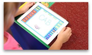 Kindergarten students use iPads to help them spell.